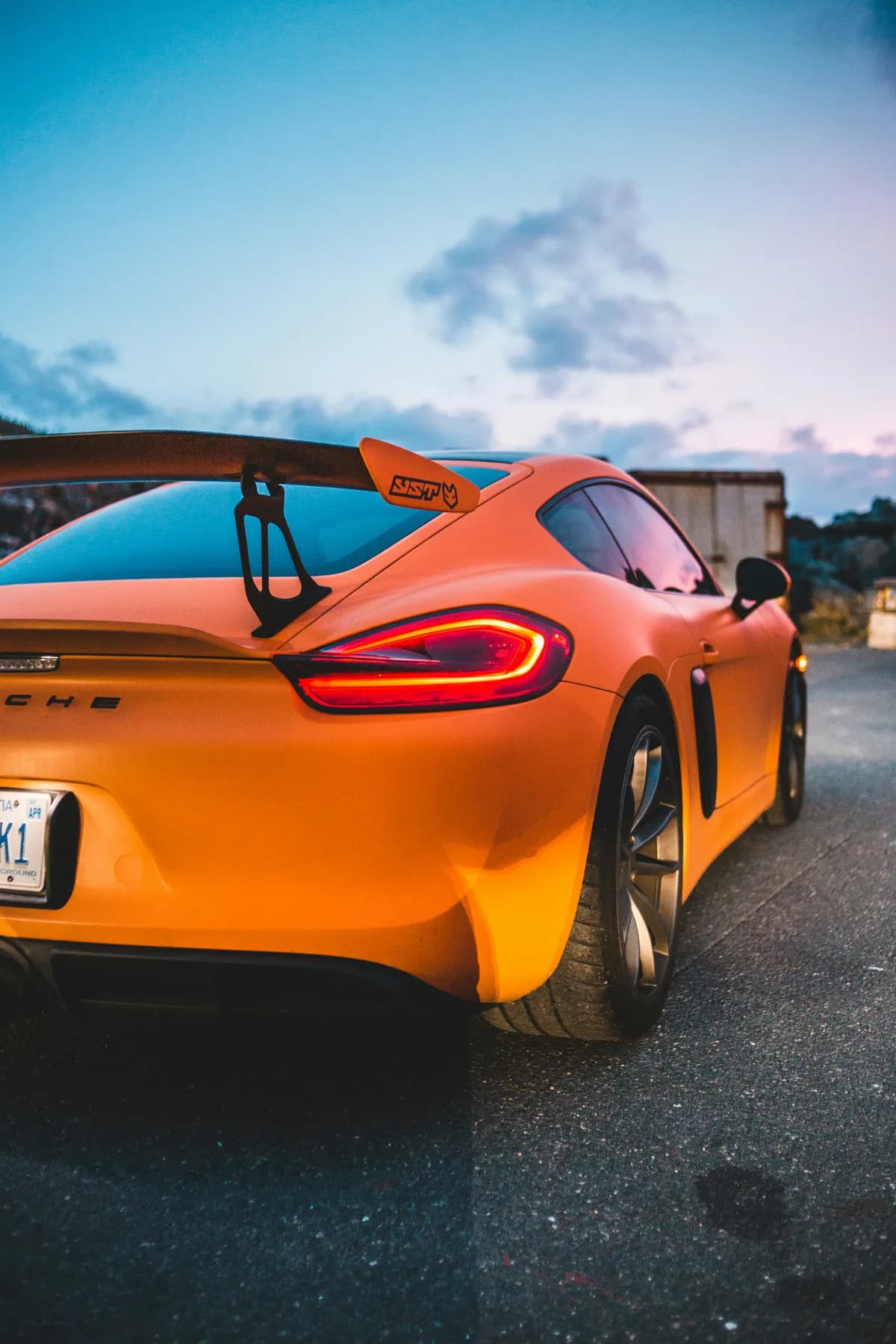 An orange Porsche Cayman GT4 at dusk